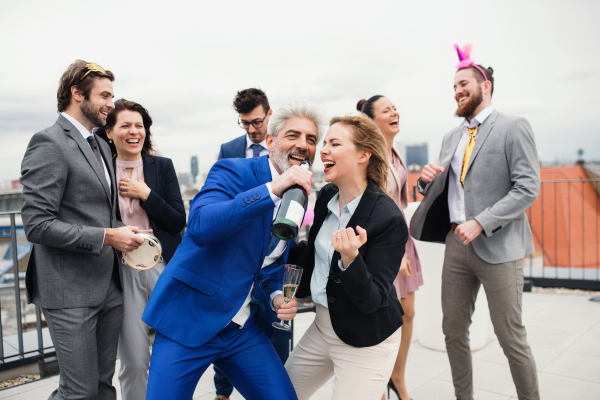 A large group of joyful businesspeople having a party outdoors on roof terrace in city.