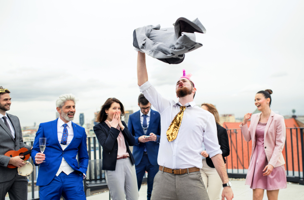 A large group of joyful businesspeople having a party outdoors on roof terrace in city.