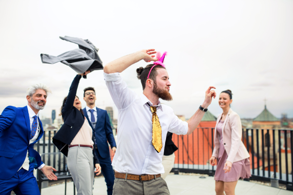 A large group of joyful businesspeople having a party outdoors on roof terrace in city.