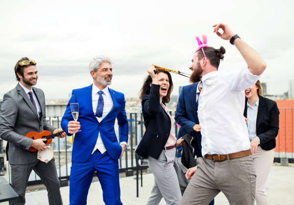 A large group of joyful businesspeople having a party outdoors on roof terrace in city.