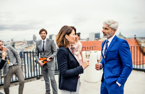 A large group of joyful businesspeople having a party outdoors on roof terrace in city.