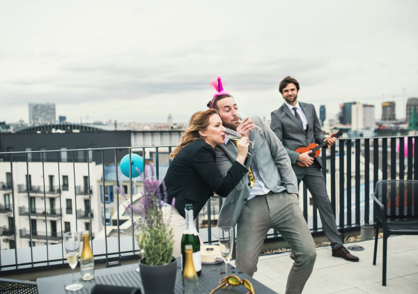 A large group of joyful businesspeople having a party outdoors on roof terrace in city.