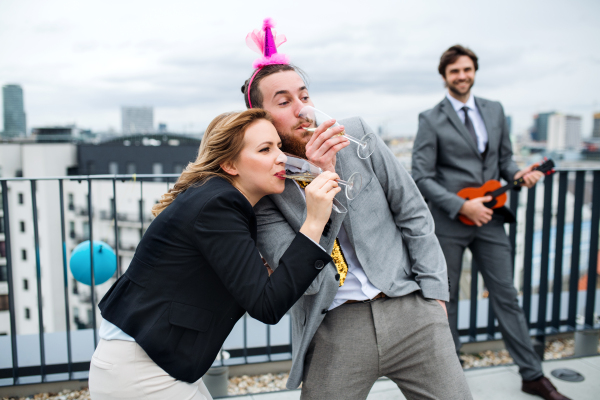 A large group of joyful businesspeople having a party outdoors on roof terrace in city.