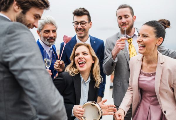 A large group of joyful businesspeople having a party outdoors on roof terrace in city.