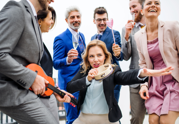 A large group of joyful businesspeople having a party outdoors on roof terrace in city.