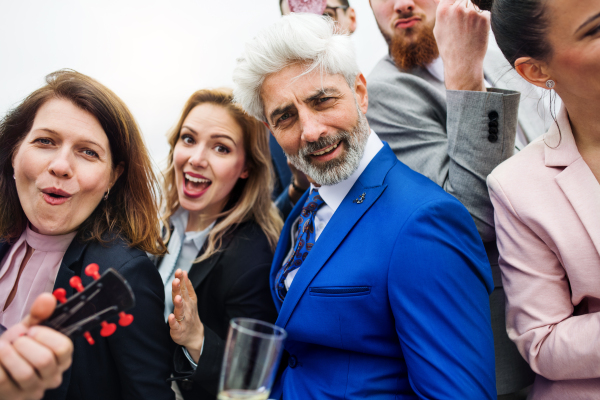 A large group of joyful businesspeople having a party outdoors on roof terrace in city.