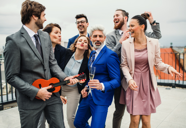 A large group of joyful businesspeople having a party outdoors on roof terrace in city.