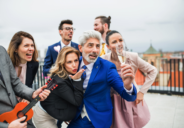 A large group of joyful businesspeople having a party outdoors on roof terrace in city.