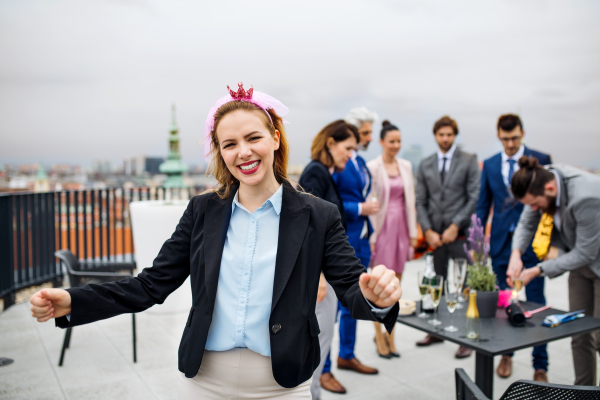 A large group of joyful businesspeople having a party outdoors on roof terrace in city.