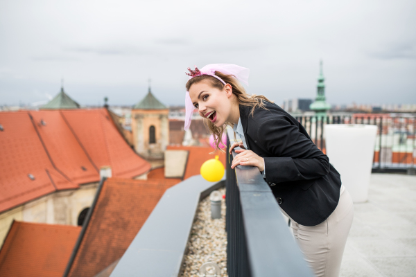 A young businesswoman with princess headband on party outdoors on roof terrace in city.