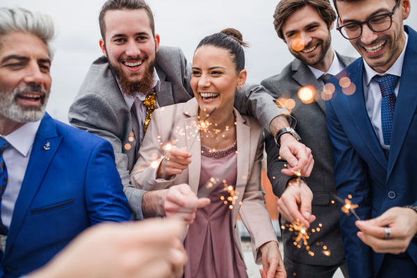 A large group of joyful businesspeople with sparklers having a party outdoors on roof terrace in city.