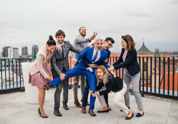 A large group of joyful businesspeople having a party outdoors on roof terrace in city.