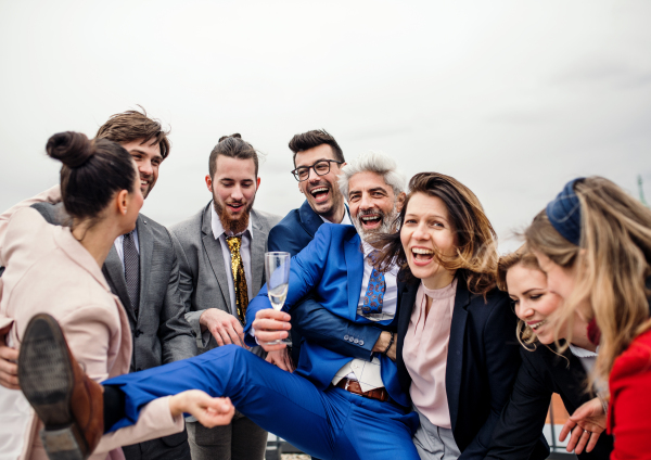 A large group of joyful businesspeople having a party outdoors on roof terrace in city.