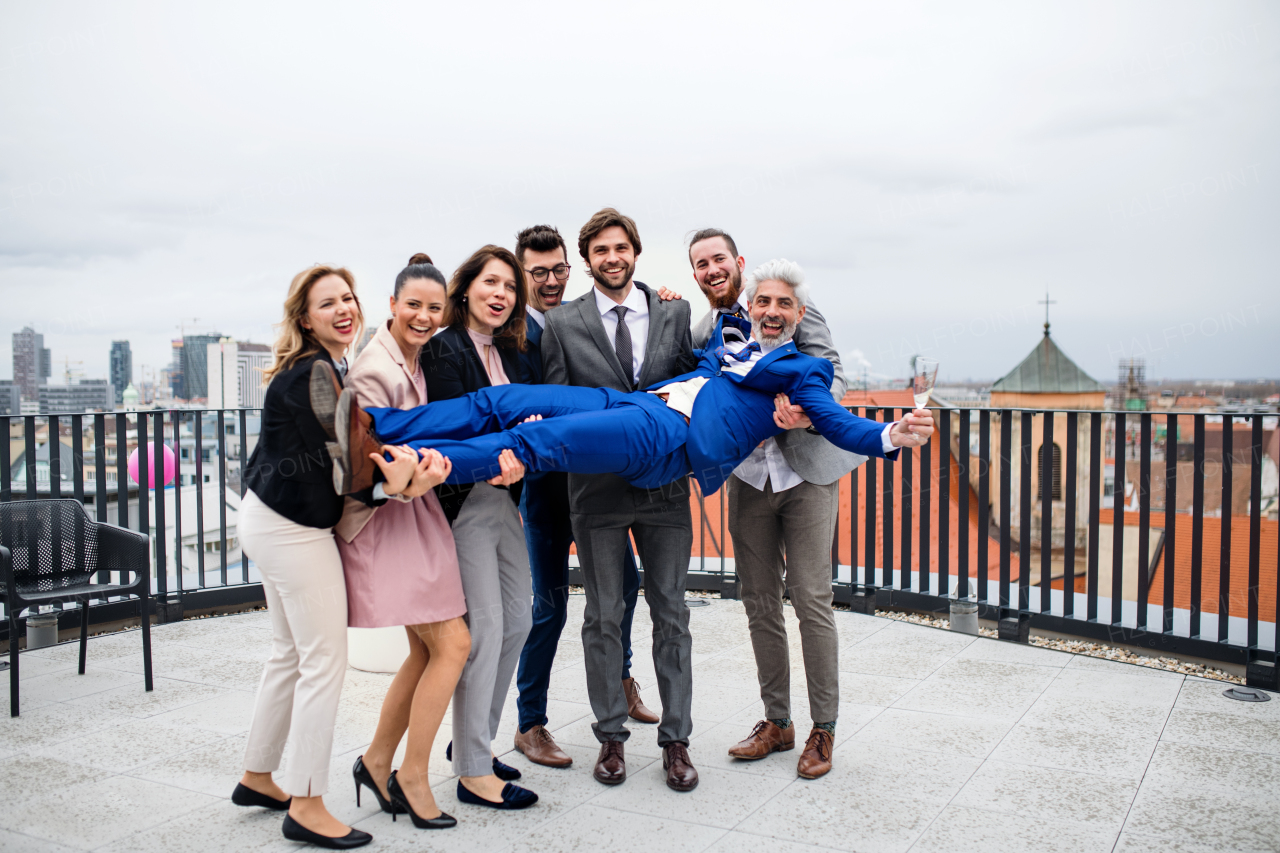 A large group of joyful businesspeople having a party outdoors on roof terrace in city.