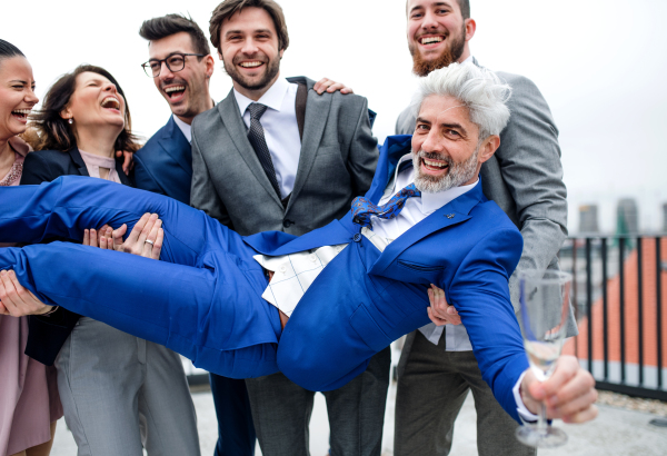 A large group of joyful businesspeople having a party outdoors on roof terrace in city.