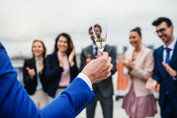 A large group of joyful businesspeople having a party outdoors on roof terrace in city.