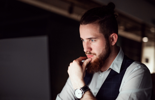 A portrait of young businessman in an office at night, working. Copy space.