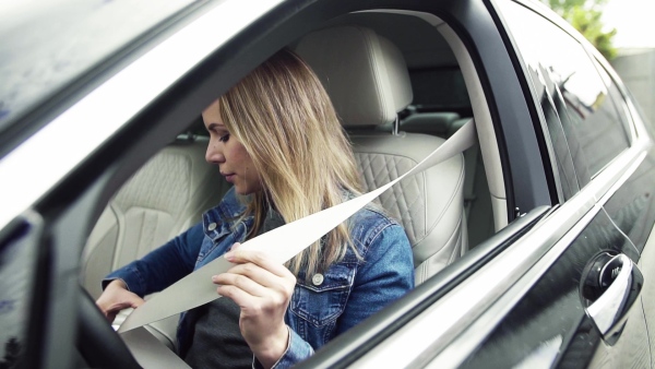 A young woman sitting in car, fastening seat belt. Slow motion.