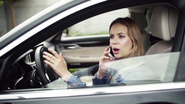 Young woman with smartphone sitting in car, making a phone call. Slow motion.