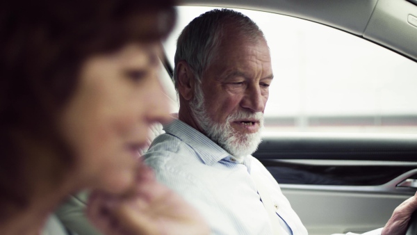 A happy senior couple sitting in car, talking.