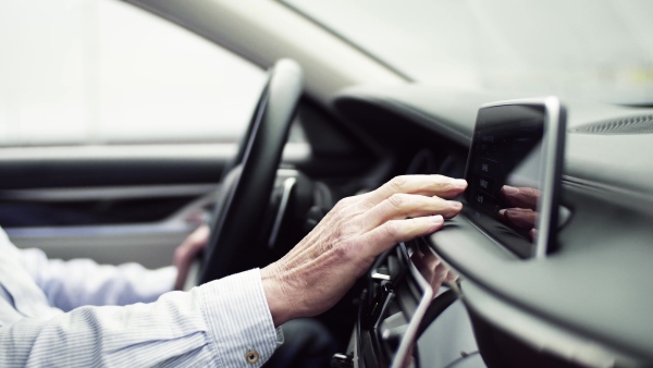 Midsection of hands of unrecognizable man driver sitting in car, setting radio or navigation.