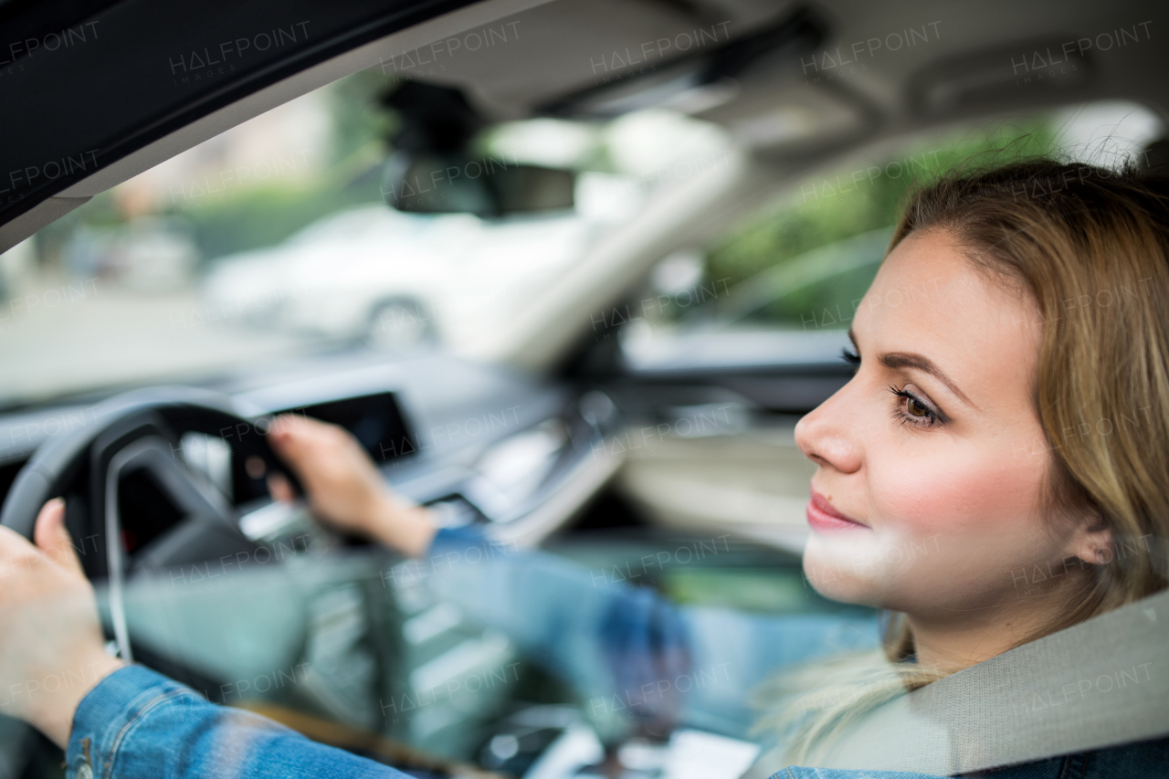 A young woman driver sitting in car. Shot through glass.