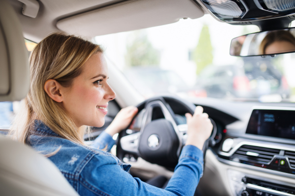 Young woman driver sitting in car, driving. Copy space.