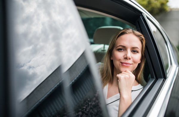 Business woman sitting on back seats in taxi car, looking out. Copy space.