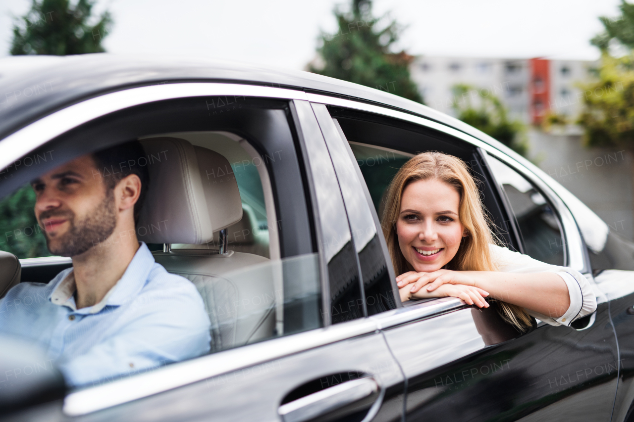 A business woman sitting on back seats in taxi car, looking out of window.