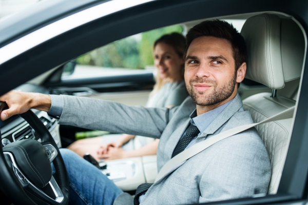 A young couple sitting in a car, driving.