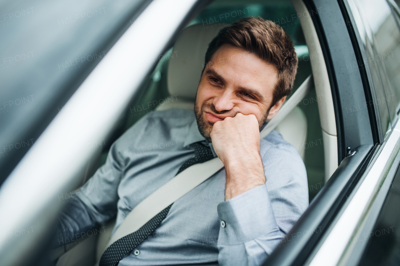 A young bored business man with shirt and tie sitting in car.