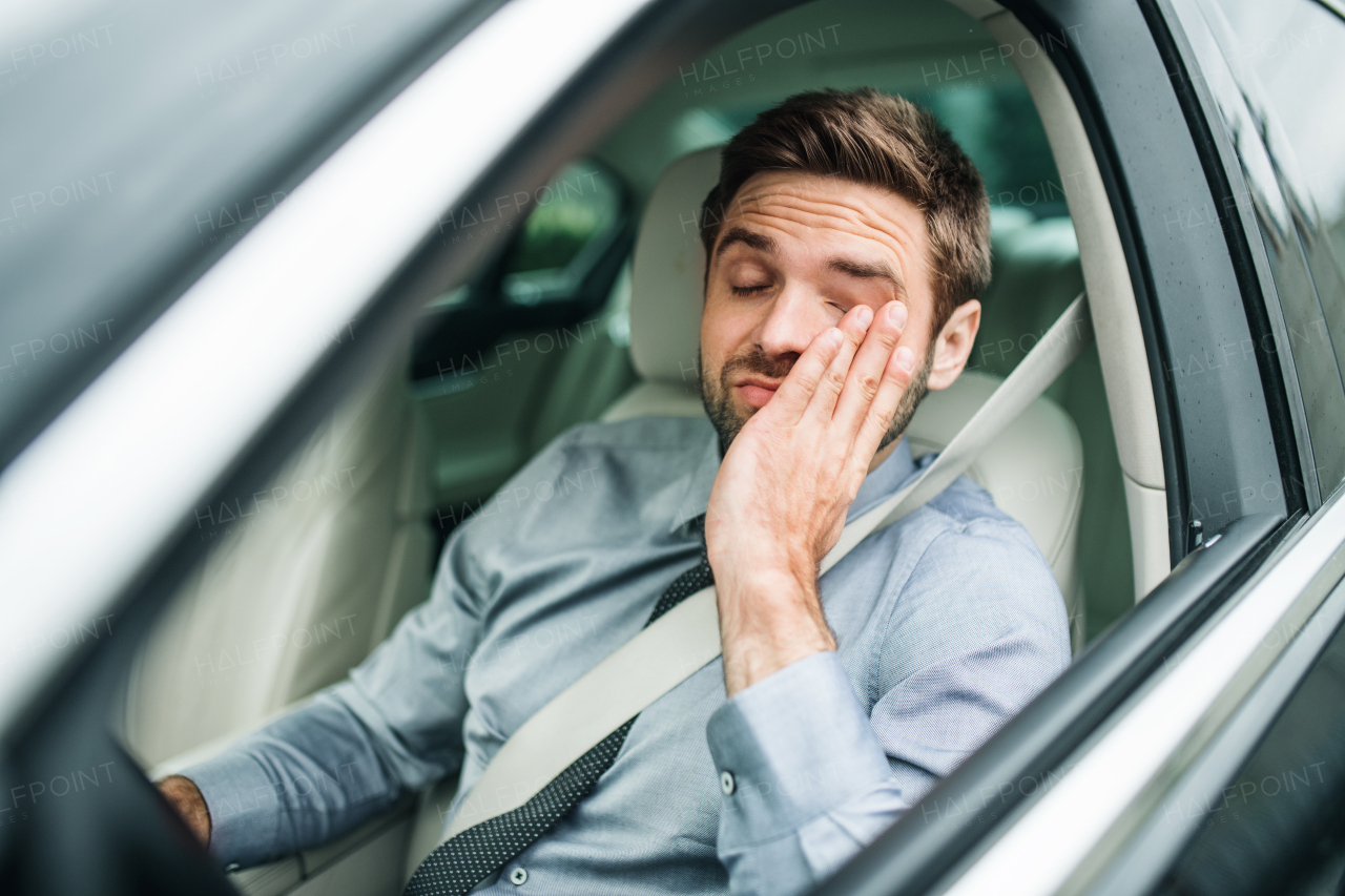 A young bored business man with shirt and tie sitting in car.