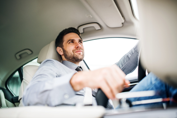 Young businessman with shirt and tie sitting in brand new car, driving.