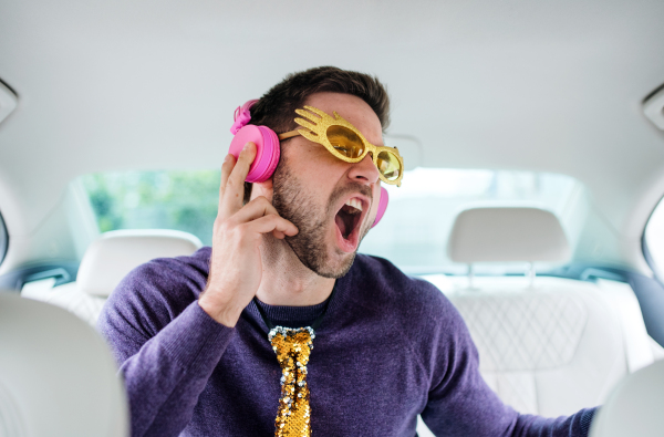 A cheerful man with party accessories sitting in car, having fun.