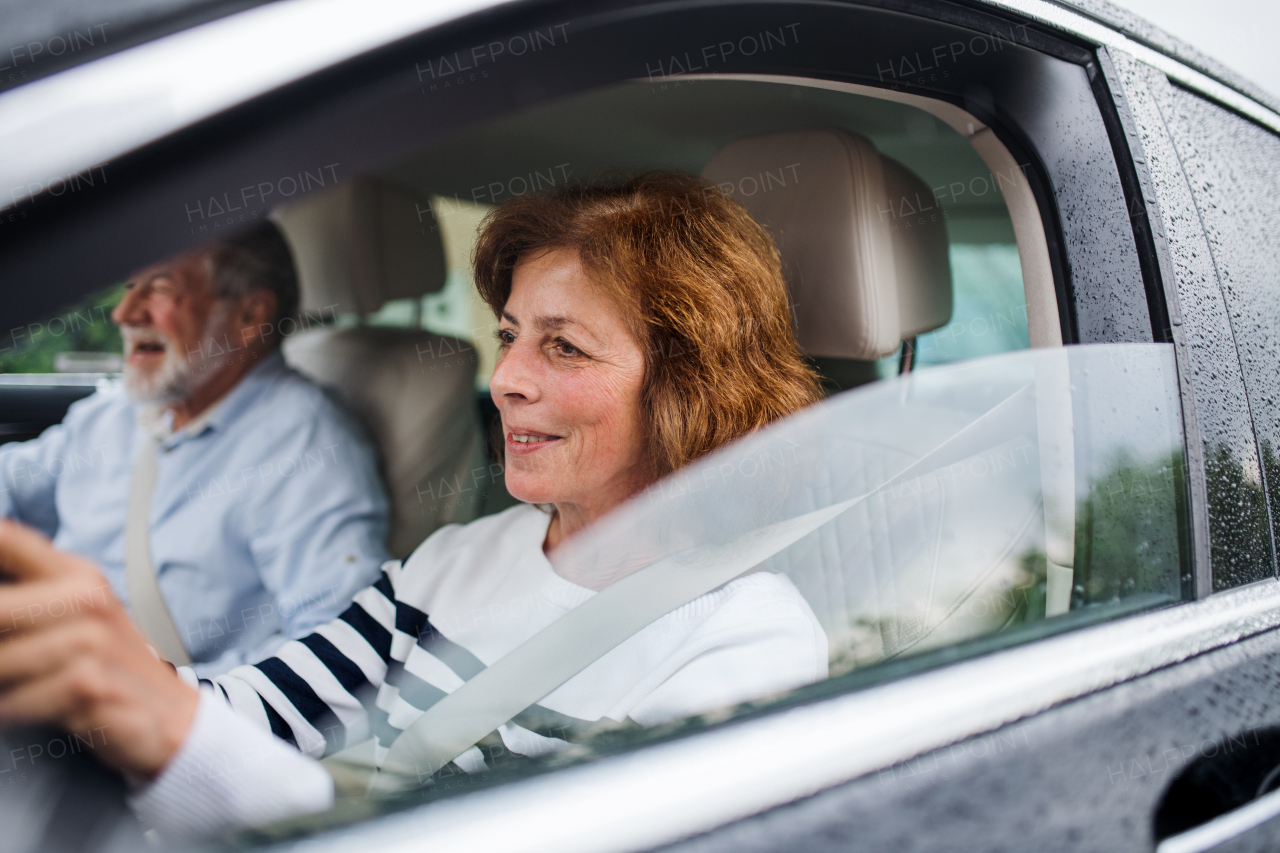 A happy senior couple sitting in car, driving and talking.