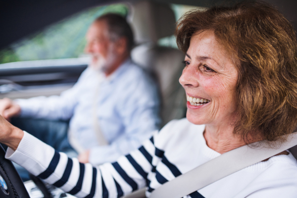 A happy senior couple sitting in car, driving and talking.