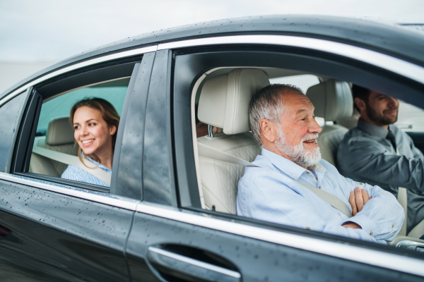 A multigeneration family sitting in car, driving and talking.