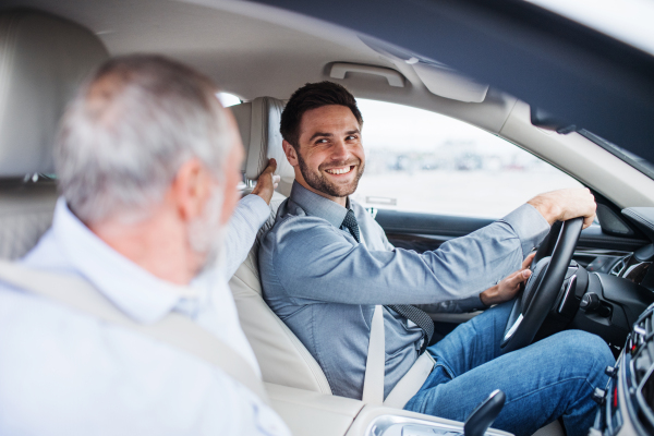 Senior father and son sitting in car, driving and talking.