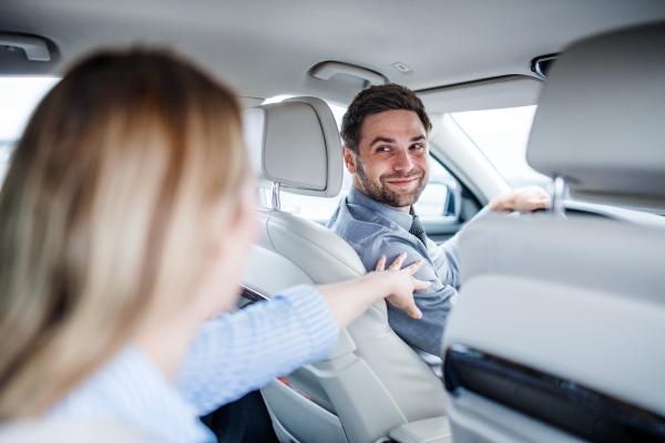 A happy young couple sitting in car, talking.