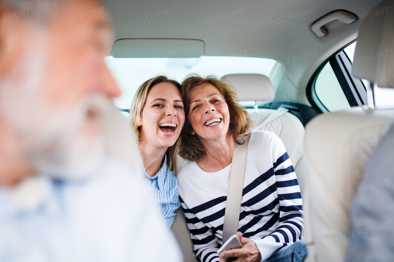 Cheerful male and female adults sitting in car, going on a trip.