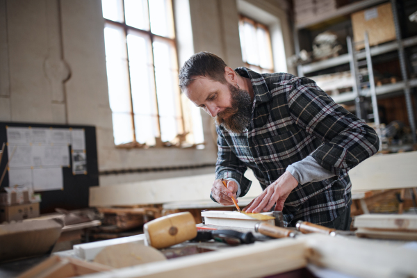 A portrait of mature male carpenter working on his product. Small business concept.