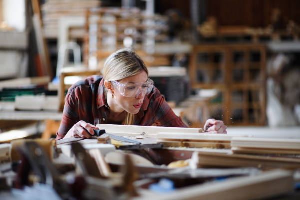 A portrait of female carpenter with goggles working on her product. Small business concept.