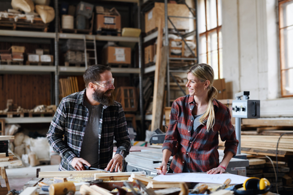 Two carpenters a man and a woman talking about design of products. Small business concept.