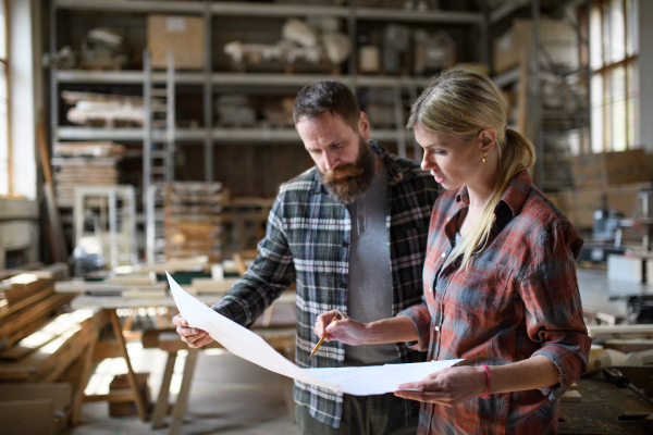 Two carpenters a man and a woman talking about design of products. Small business concept.