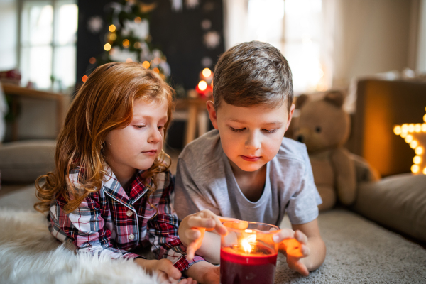 Small girl lying and sleeping on sofa indoors at Christmas, holding candle.