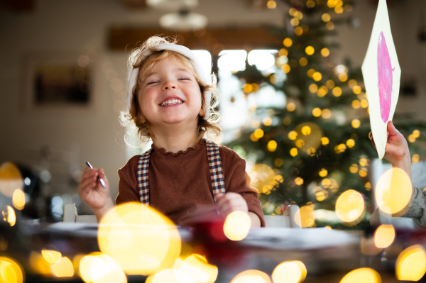 Portrait of happy small girl indoors at home at Christmas, laughing.