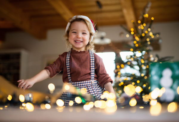 Portrait of happy small girl indoors at home at Christmas, laughing.