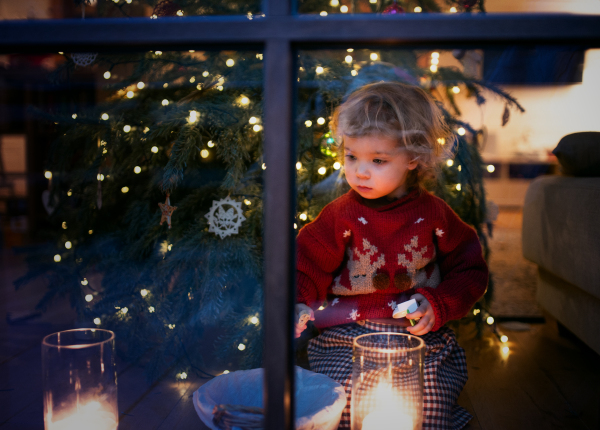 Portrait of happy small girl indoors at home at Christmas, playing.