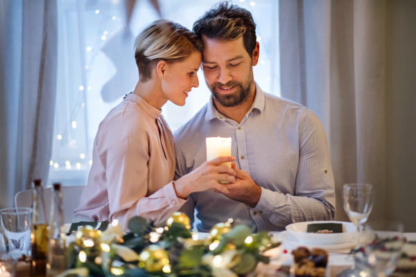 Front view portrait of happy couple indoors at the table celebrating Christmas.