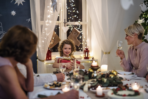 Multi-generation family indoors celebrating Christmas together, sitting at the table.